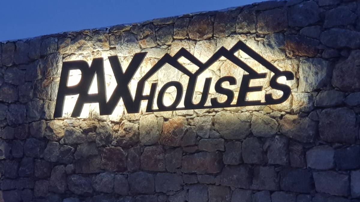 Natpis Pax Houses na kamenom zidu, osvijetljen noću
